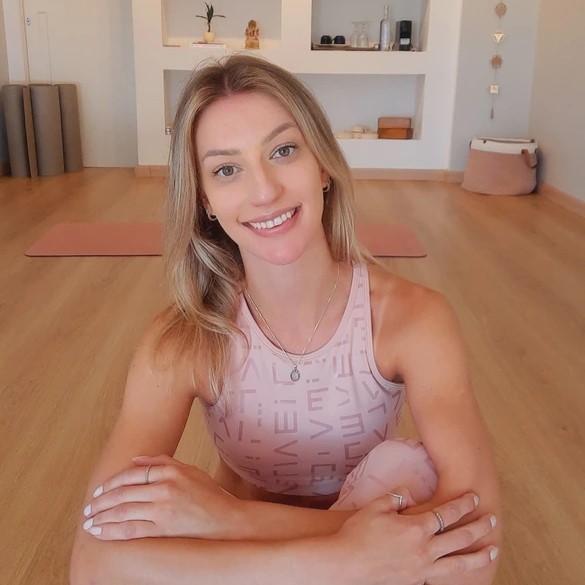 Gabi Gabler sorrindo, sentada no tapete de Yoga em seu estúdio